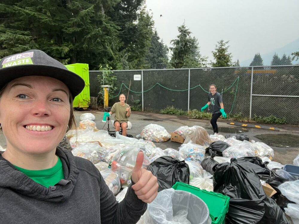 Person with a thumbs up in front of bags of trash and two other people